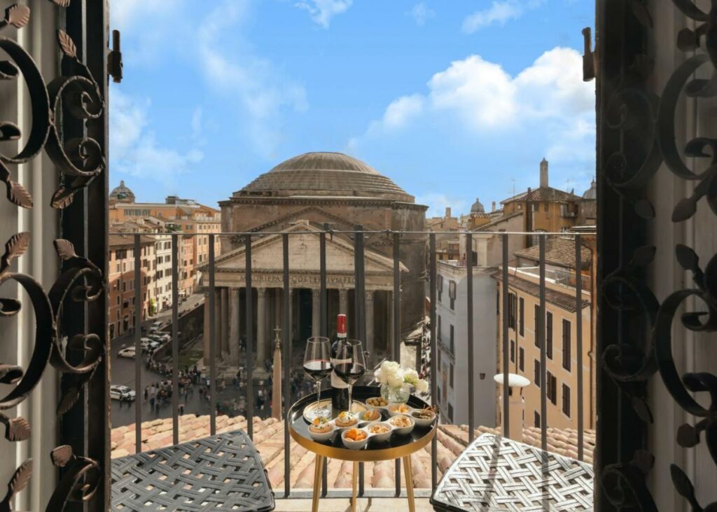 View from the balcony of the room overlooking the Pantheon, two chairs, a table with food and wine.