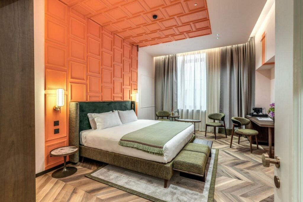 Warmly decorated hotel room with orange walls and wooden floors.