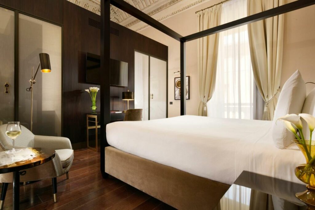 A luxurious hotel room featuring a four poster bed and a comfortable chair.