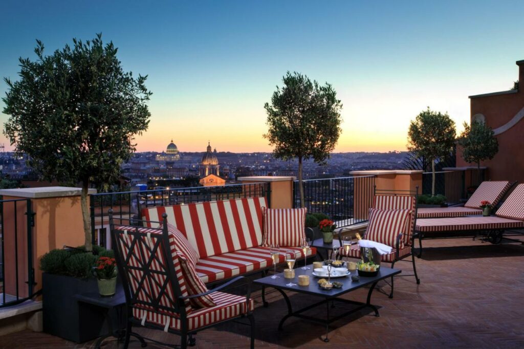 Glamorous rooftop terrace with lounge chairs and tables, offering a stunning city view.