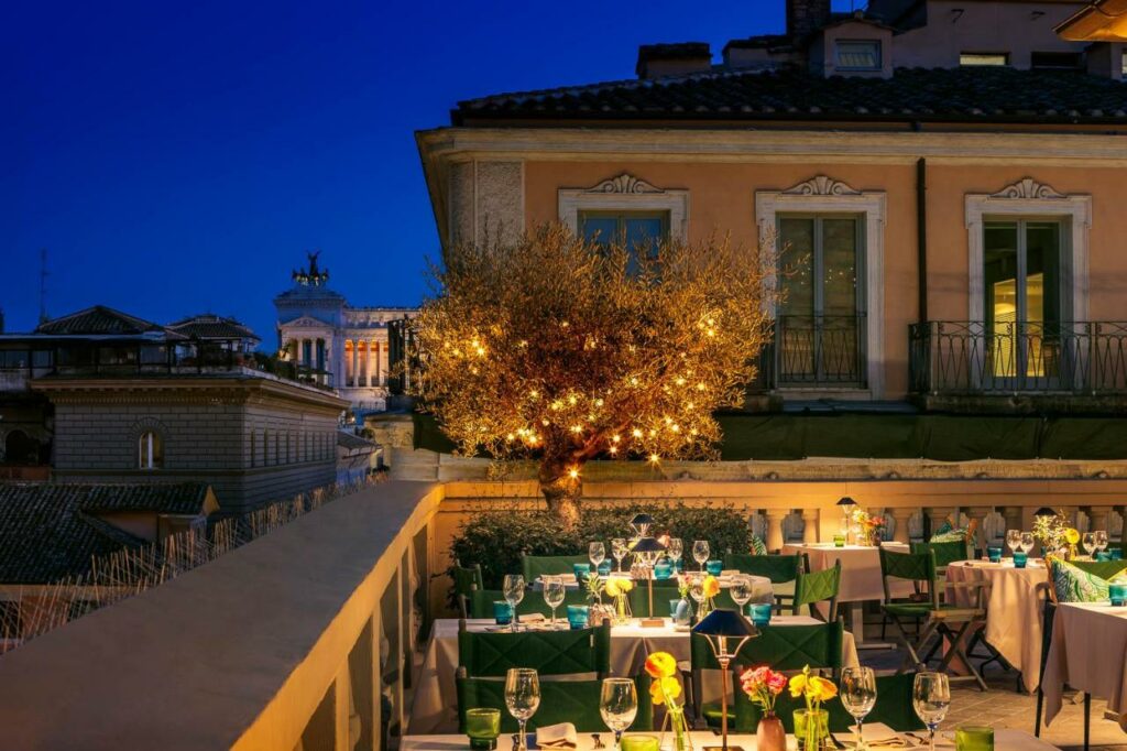Beautiful rooftop restaurant of the hotel in the evening with set tables and illuminated tree lanterns.